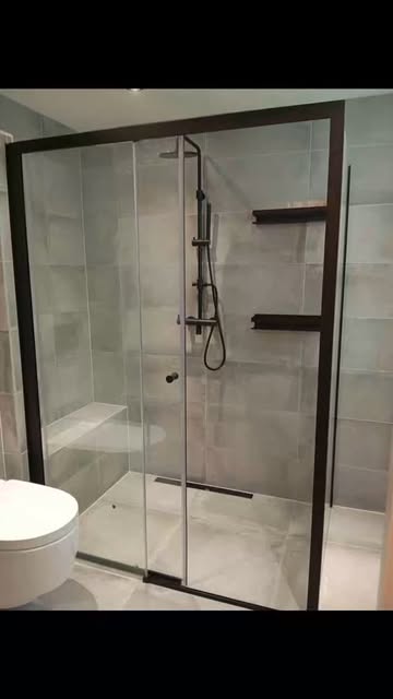 Dusche mit schwarzen Glasrahmen und Armaturen vor hellgrauen Wandplatten, Vorschaubild eines Instagram-Videos