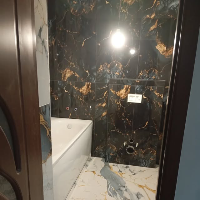Badezimmer während der Umsetzung mit dunkel gemusterten Wandplatten und einer weissen Badewanne